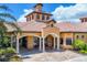 Welcoming clubhouse entrance featuring classic architecture and lush tropical landscaping at 11103 Batello Dr, Venice, FL 34292