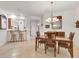 Elegant dining room with a wooden table and chairs, chandelier, and tile flooring, open to the adjacent kitchen at 11103 Batello Dr, Venice, FL 34292