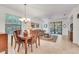 Open concept living and dining room with tiled floors, chandelier, and sliding glass doors to outdoor area at 11103 Batello Dr, Venice, FL 34292