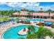 Overhead view of sunny community pool with tables, chairs, umbrellas, multiple seating areas, and landscaping at 11103 Batello Dr, Venice, FL 34292