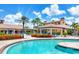 Bright and sunny community pool with palm trees, lounge chairs, red flowers and covered seating areas at 11103 Batello Dr, Venice, FL 34292