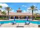 Inviting community pool and sun deck with tables, chairs, and umbrellas, flanked by palm trees on a sunny day at 11103 Batello Dr, Venice, FL 34292
