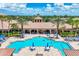 Overhead view of sunny community pool and sun deck with tables, chairs, and umbrellas, flanked by palm trees at 11103 Batello Dr, Venice, FL 34292