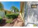 The side of the home shows lush tropical landscaping, brick paver walkway and yellow siding at 11624 Garessio Ln, Sarasota, FL 34238