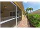 Enclosed patio leading to a brick-paved walkway with manicured greenery and palm tree at 11624 Garessio Ln, Sarasota, FL 34238