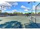A vibrant tennis court is surrounded by lush greenery and clear blue skies at 11624 Garessio Ln, Sarasota, FL 34238