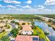 Aerial view of a waterfront property with a tile roof, lush trees, and landscaping at 11986 Granite Woods Loop, Venice, FL 34292