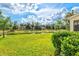 Lush backyard with a view of the waterfront, palm trees, and partly cloudy skies at 11986 Granite Woods Loop, Venice, FL 34292