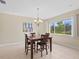 Dining room with modern table set, chandelier, and large window with view of the lush outdoor landscaping at 11986 Granite Woods Loop, Venice, FL 34292