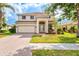 Two-story home featuring a two-car garage, a welcoming front porch, and a well-manicured lawn with beautiful landscaping at 11986 Granite Woods Loop, Venice, FL 34292