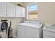 Bright laundry room with white cabinetry, sink, and front load washer and dryer at 11986 Granite Woods Loop, Venice, FL 34292