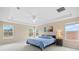 Comfortable main bedroom features three large windows, tray ceiling, and a ceiling fan at 11986 Granite Woods Loop, Venice, FL 34292