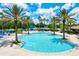 Large community pool surrounded by palm trees, lounge chairs, and vibrant blue umbrellas under a sunny sky at 11986 Granite Woods Loop, Venice, FL 34292