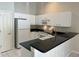 A kitchen boasting white cabinets, black countertops, and essential appliances for convenient meal preparation at 1204 L Pavia Blvd # 1204, Venice, FL 34292