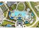 Stunning aerial view of resort-style pool with lush landscaping, amenities, and inviting blue umbrellas at 12390 Wellen Golf St # 203, Venice, FL 34293