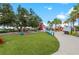 Lush green lawn with colorful seating and palm trees in a vibrant community space at 12390 Wellen Golf St # 203, Venice, FL 34293