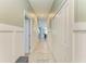 Bright hallway with tile floors, white trim and paneled walls leading to the kitchen at 12390 Wellen Golf St # 203, Venice, FL 34293
