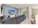 Bright living room with a large television, comfortable sectional couch, and sliding glass doors to the lanai at 12390 Wellen Golf St # 203, Venice, FL 34293