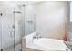 Modern bathroom with glass enclosed shower and soaking tub with white and gray tile at 12871 Cinqueterre Dr, Venice, FL 34293