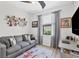 Comfortable living room with gray sofa, unique metal wall art, and a window with natural light at 12871 Cinqueterre Dr, Venice, FL 34293