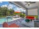 Screened lanai featuring a pool, hot tub, dining area, and cozy seating with views of the lush greenery at 12871 Cinqueterre Dr, Venice, FL 34293