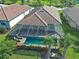 An aerial view displays the lanai, palm trees and lush landscaping of this home and neighborhood at 13016 Rinella St, Venice, FL 34293