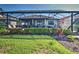 The backyard has a screen enclosed lanai, outdoor seating, grill, and manicured hedges at 13016 Rinella St, Venice, FL 34293