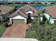 An elevated view of the home with a two-car garage, brick paver driveway and tropical landscaping at 13016 Rinella St, Venice, FL 34293
