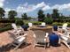 Outdoor fire pit area with white Adirondack chairs and cobalt blue accent tables overlooking lake and bridge at 13016 Rinella St, Venice, FL 34293