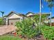 Lovely home with a brick driveway, two-car garage, and vibrant tropical landscaping at 13016 Rinella St, Venice, FL 34293