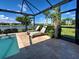 Covered lanai featuring travertine tile, lake views, and comfortable chaise lounges at 13016 Rinella St, Venice, FL 34293