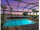 Screened-in pool and travertine lanai with colorful sunset reflecting on the lake at 13016 Rinella St, Venice, FL 34293