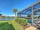 Covered lanai and pool with serene lake view, enhanced by tropical landscaping and palm trees at 13016 Rinella St, Venice, FL 34293