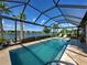 Inviting screened-in pool with lake view, sun loungers, and tropical plants at 13016 Rinella St, Venice, FL 34293