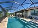 Screened pool with travertine tile, outdoor kitchen, and serene lake view at 13016 Rinella St, Venice, FL 34293