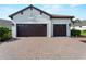 Spacious three-car garage with dark brown doors and a wide brick driveway at 13056 Steinhatchee Loop, Venice, FL 34293