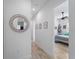 Hallway with art and light colored wood look floors leads to bedroom with ceiling fan at 13056 Steinhatchee Loop, Venice, FL 34293