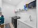 Laundry room features modern washer and dryer, sink, storage cabinets, and wire rack at 13056 Steinhatchee Loop, Venice, FL 34293
