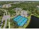 Overhead view of well-maintained blue and green tennis courts next to a lake and parking lot in a scenic community at 13056 Steinhatchee Loop, Venice, FL 34293