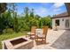 Inviting backyard patio with rocking chairs, fire pit, and lush landscaping at 13280 Campanile Ct, Venice, FL 34293