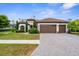 Charming home with a tile roof, three-car garage, paver driveway, and manicured lawn at 13280 Campanile Ct, Venice, FL 34293