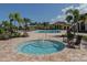 A community hot tub is surrounded by pavers and seating, set against a backdrop of palms and a pool at 13280 Campanile Ct, Venice, FL 34293