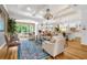Open-concept living room with elegant chandeliers, hardwood floors, and a blue patterned rug at 13280 Campanile Ct, Venice, FL 34293