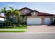 Charming single-story home boasts a red tile roof, two-car garage, paver driveway, and lush landscaping at 136 Positano Trl, Nokomis, FL 34275