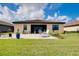 Spacious backyard with a stone patio, seating area, and lush green lawn under a partly cloudy sky at 13634 Vancanza Dr, Venice, FL 34293