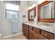 Bathroom with double sink vanity, decorative mirrors, granite countertops, and window with privacy blinds at 13634 Vancanza Dr, Venice, FL 34293