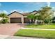 Charming single-story home boasts a three-car garage, tiled roof, brick driveway, and lush landscaping at 13634 Vancanza Dr, Venice, FL 34293