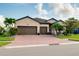 Charming single-story home boasts a three-car garage, tiled roof, brick driveway, and lush landscaping at 13634 Vancanza Dr, Venice, FL 34293