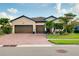 Charming single-story home boasts a three-car garage, tiled roof, brick driveway, and lush landscaping at 13634 Vancanza Dr, Venice, FL 34293