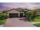 Charming single-story home boasts a three-car garage, tiled roof, brick driveway, and lush landscaping at 13634 Vancanza Dr, Venice, FL 34293